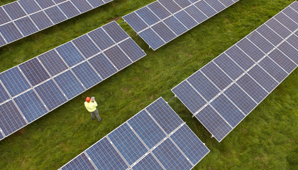 Engineer checking a solar farm site, aerial view