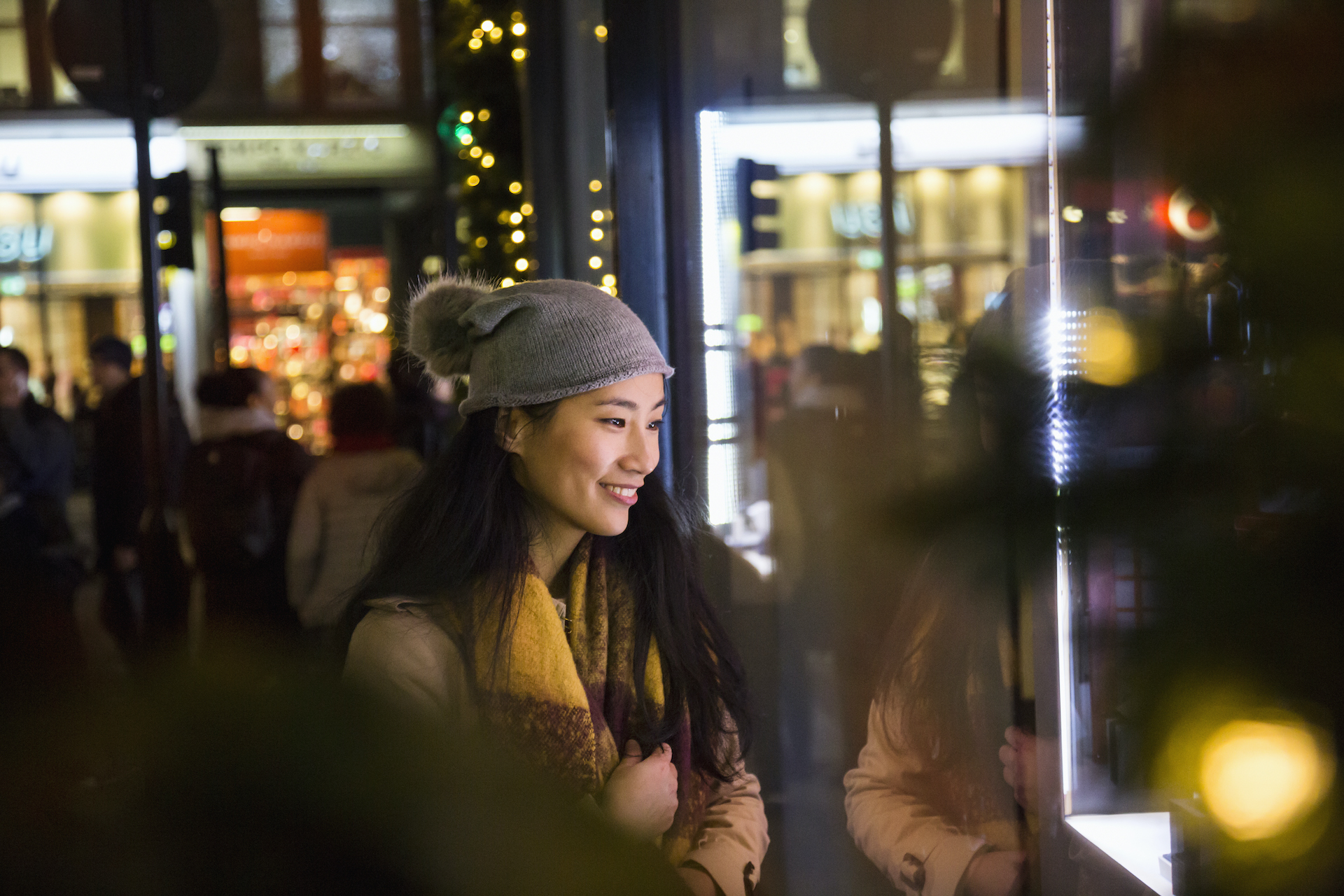 Woman looks in shop window at night time