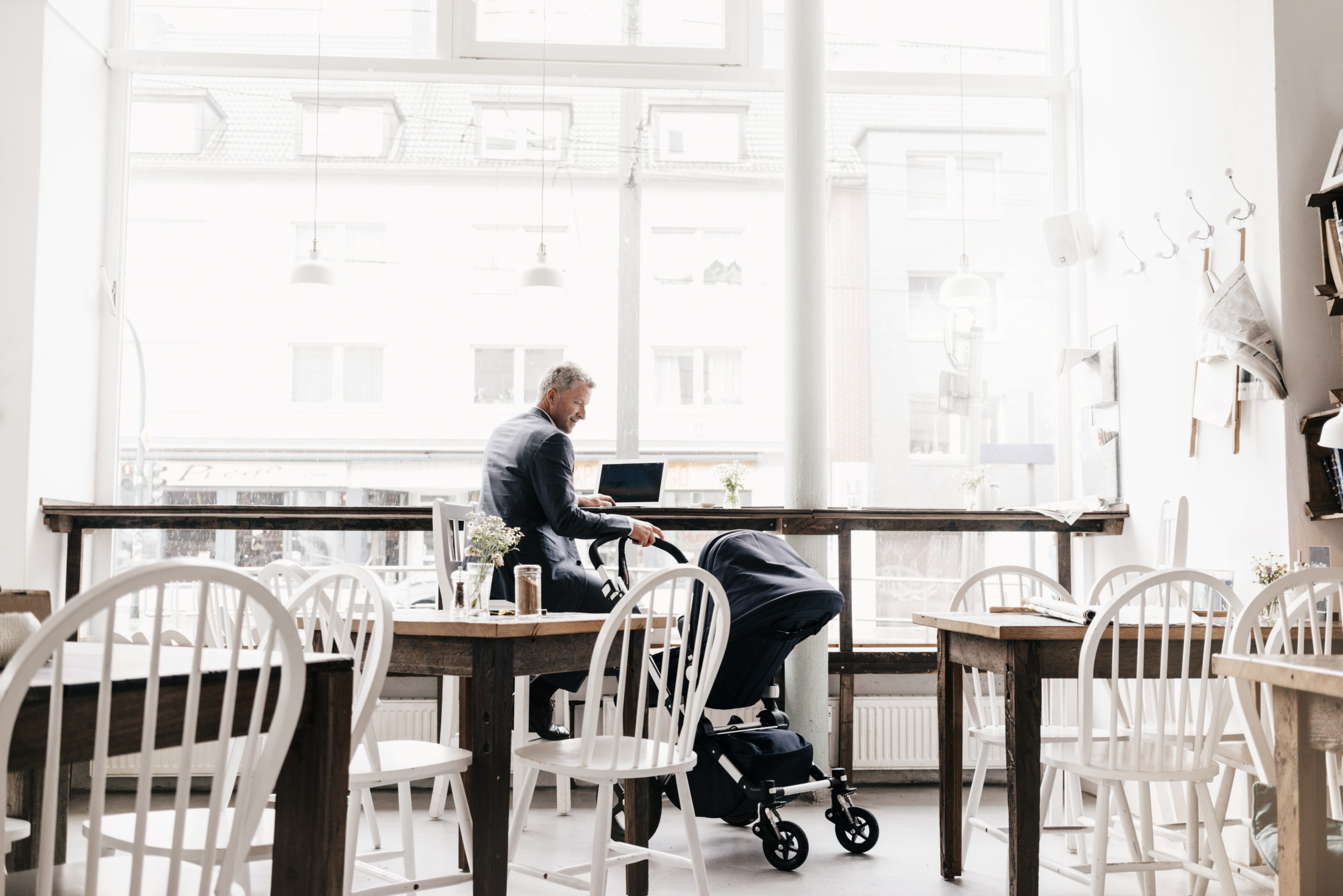 Businessman sitting in cafe with stroller.