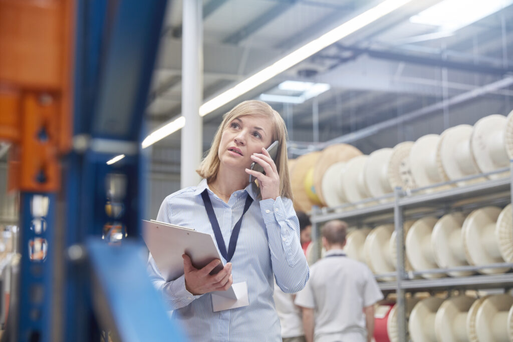 Supervisor with clipboard talking on cell phone in fiber optics factory