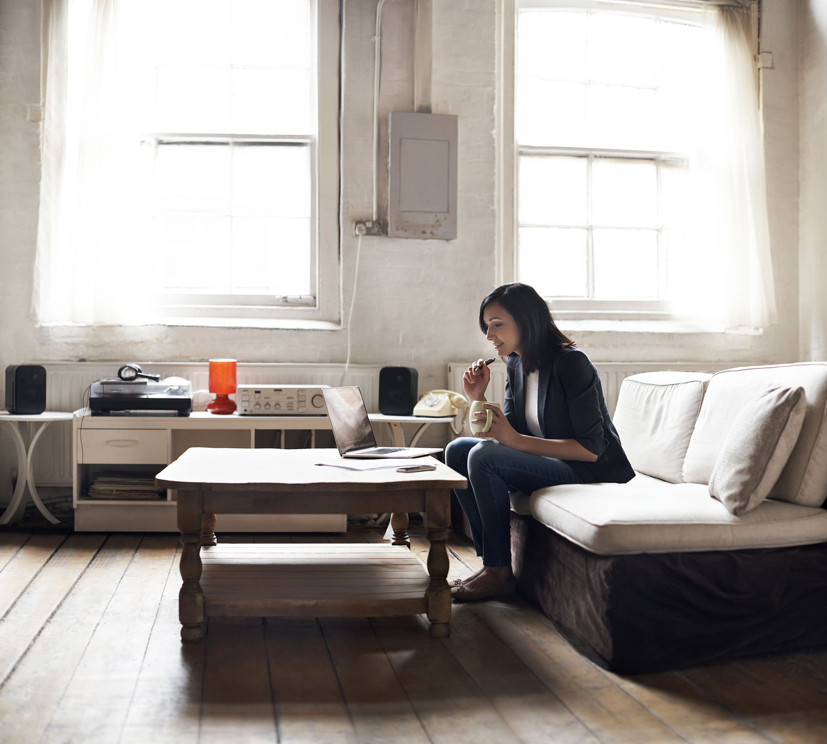 Woman sitting on sofa using laptop in her cozy loft apartment