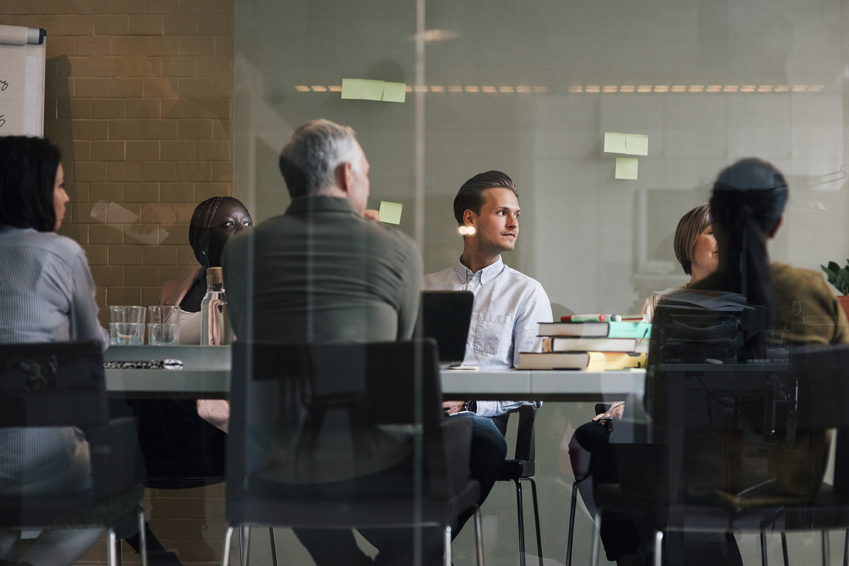 Mehrere Personen sitzen in einem Meeting Raum um einen Tisch.