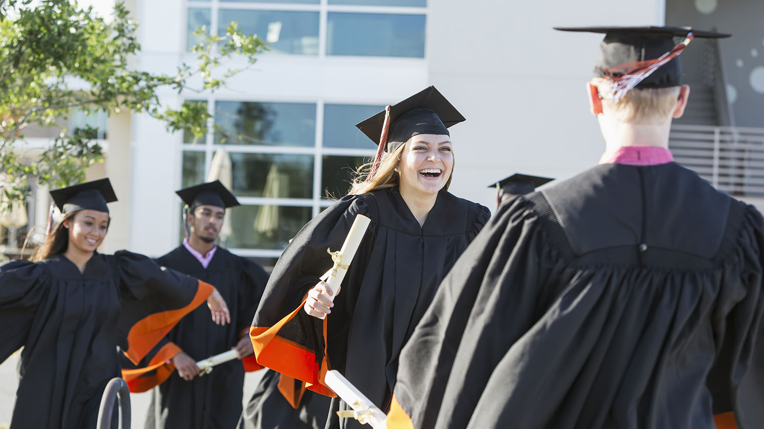 Graduates in gowns and caps celebrating after graduation ceremony.