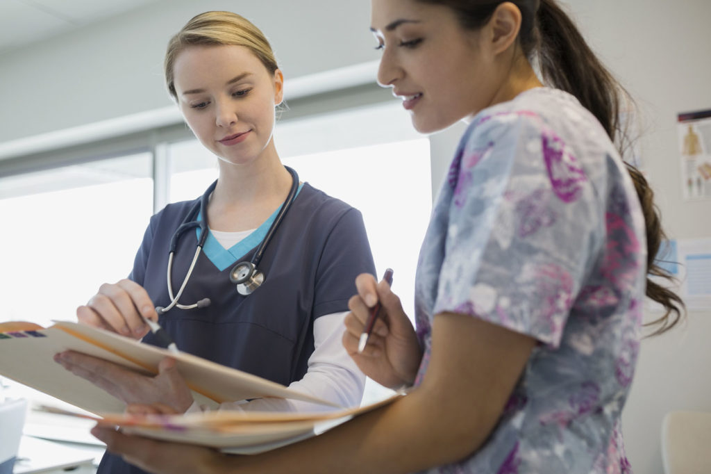 Two nurses compare medical records.