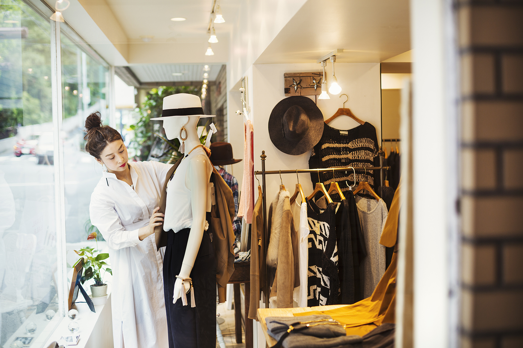 Woman working in a fashion boutique in Tokyo, Japan, dressing a mannequin.