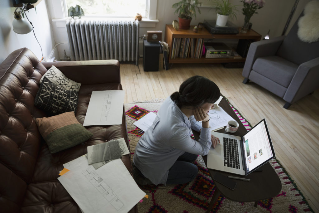 Female architect using laptop in living room.