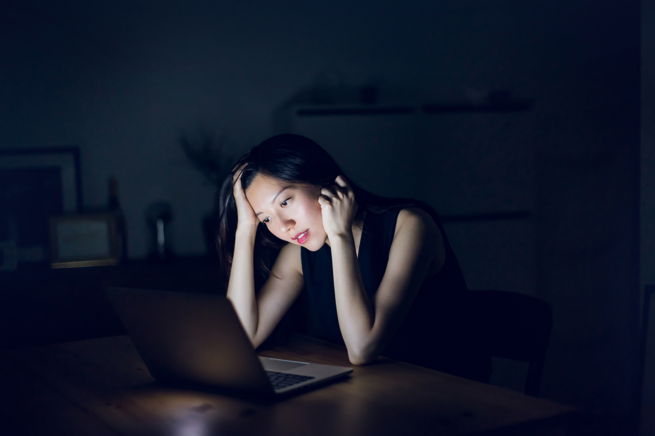 Stressed and frustrated businesswoman working on laptop till late at work