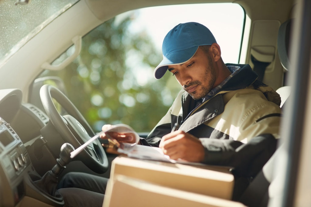 Shot of a delivery man reading addresses while sitting in a delivery van