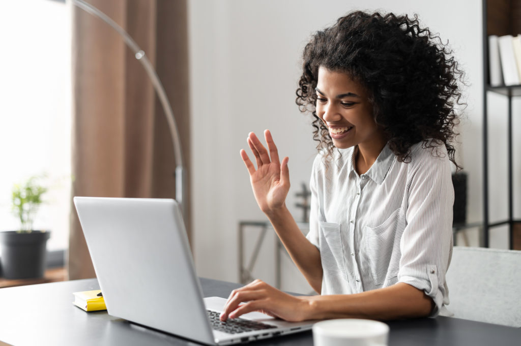 Business woman waving, smiling at the laptop screen