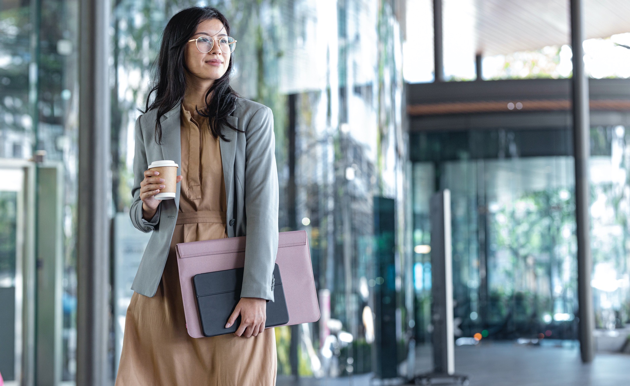 Outdoor shot of a smiling businesswoman holding coffee and files.