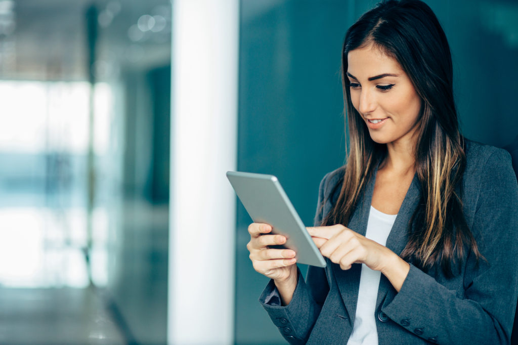 Woman in business attire scrolling on her tablet