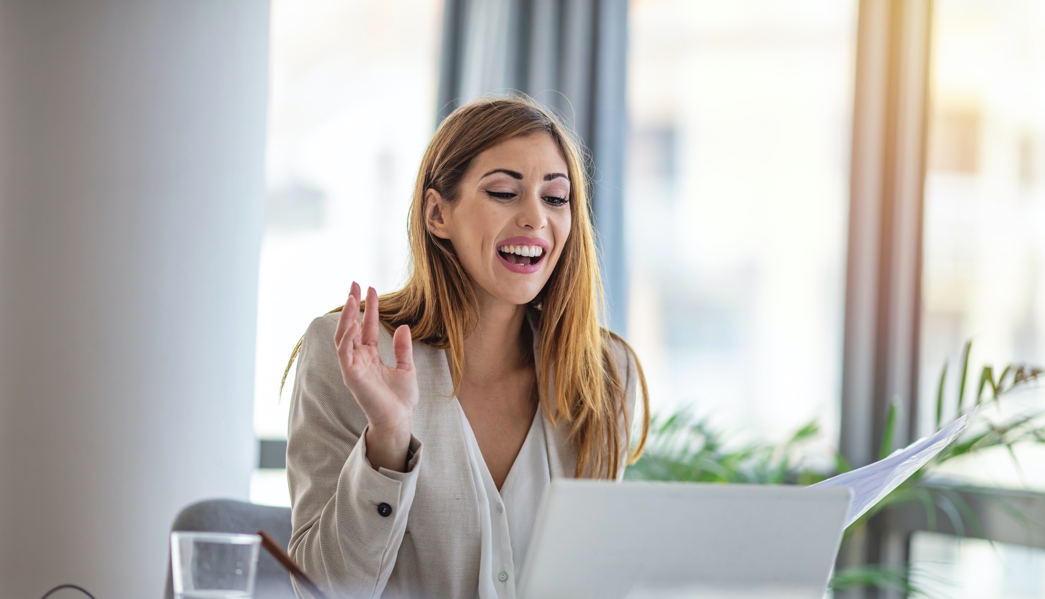 Woman smiles and waves as she participates in a video conference. 