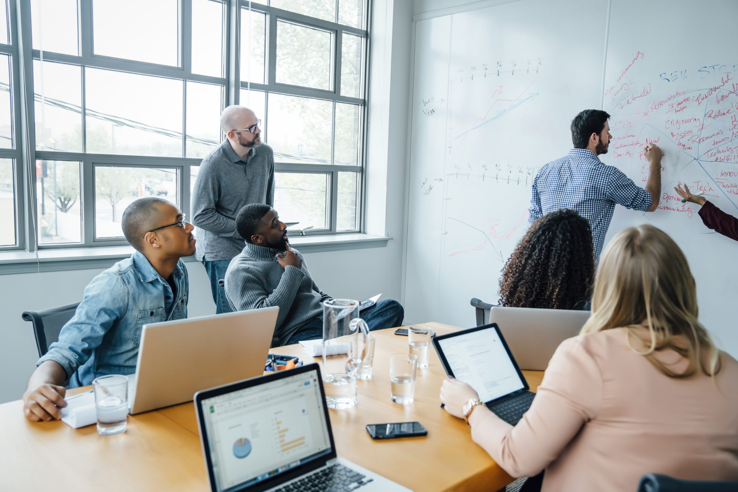 Co-workers using a whiteboard in a meeting.