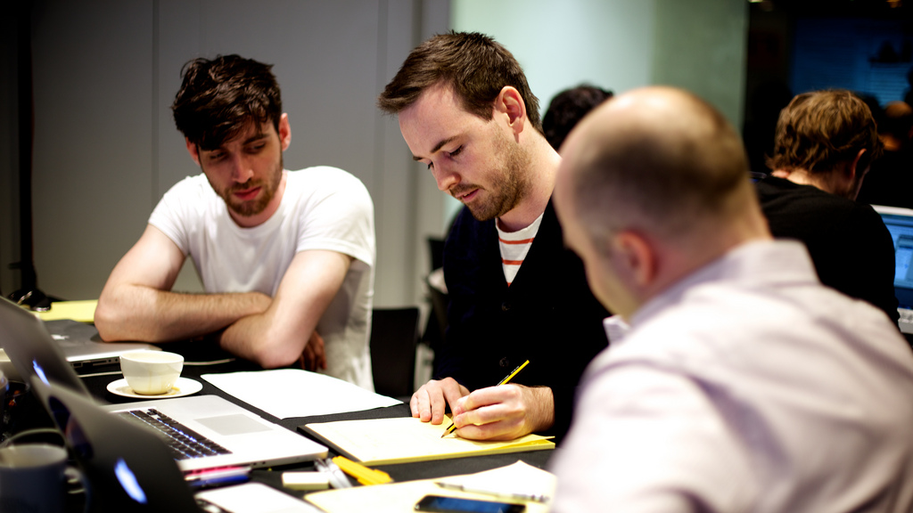 Coworkers with pen and paper taking notes during a meeting