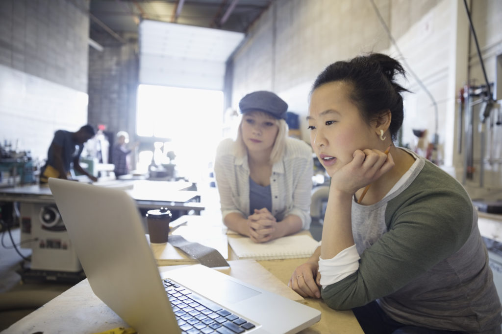 Female design professional engineers brainstorming at laptop in workshop