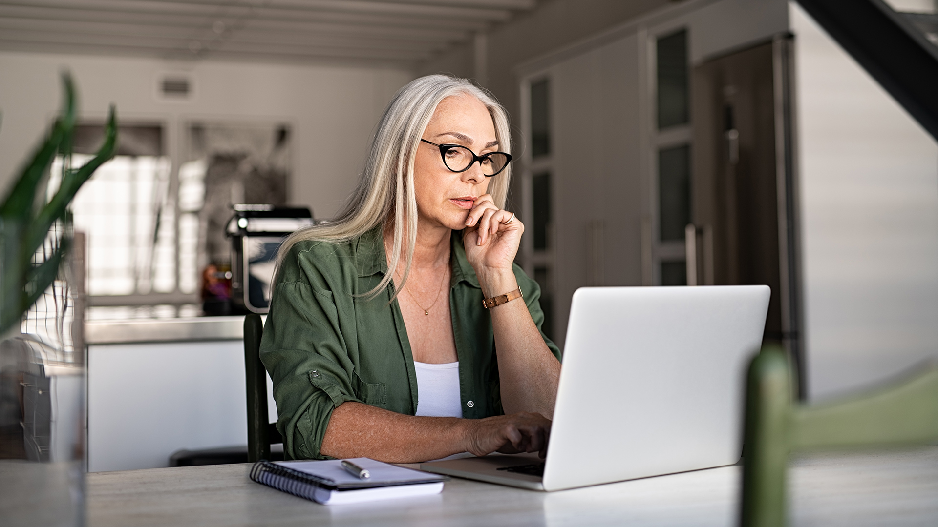 Une femme avec des lunettes regarde un écran d'ordinateur