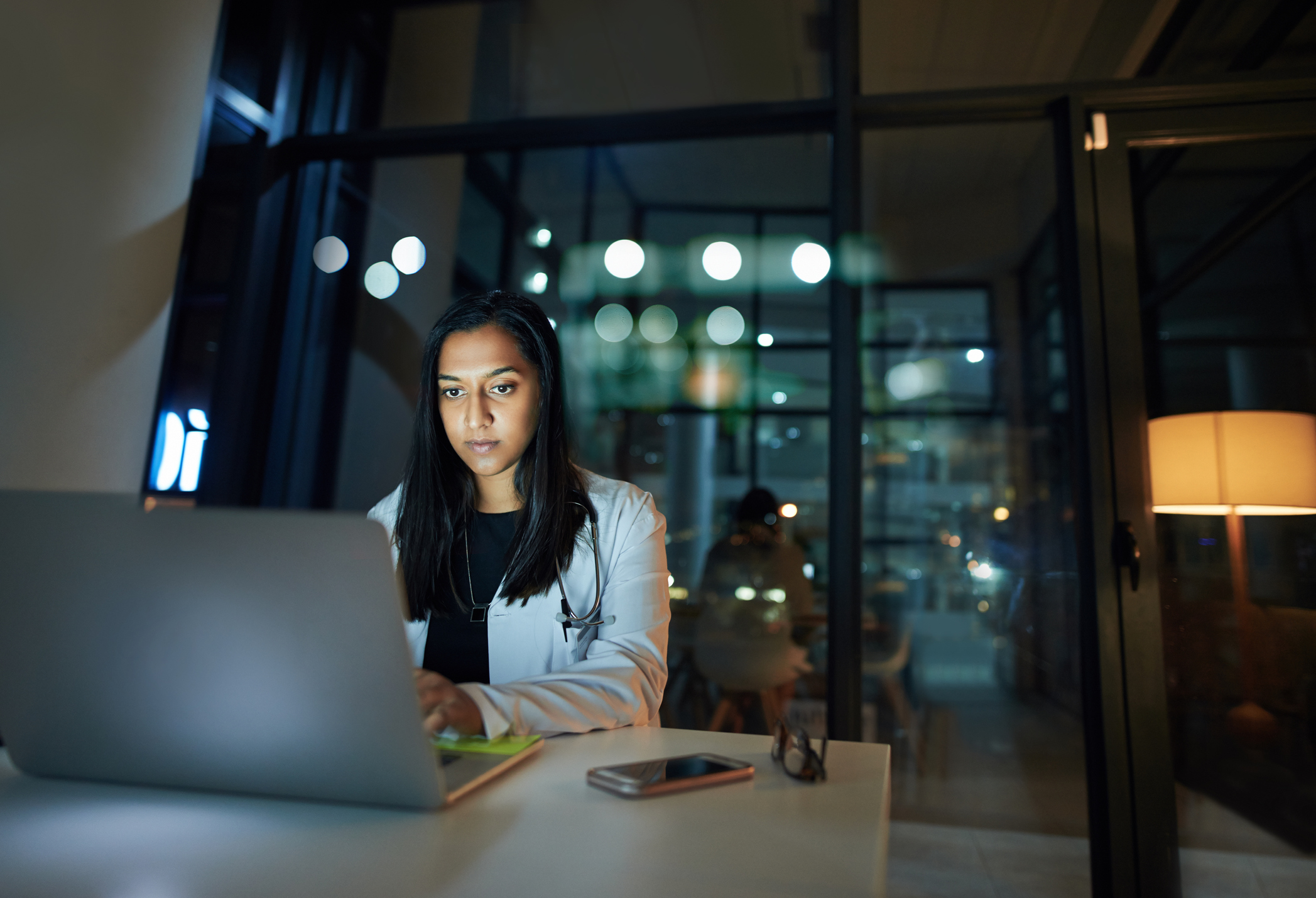 Jeune médecin utilisant un ordinateur portable dans un bureau la nuit