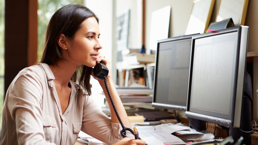 Woman on the phone at a desktop computer 