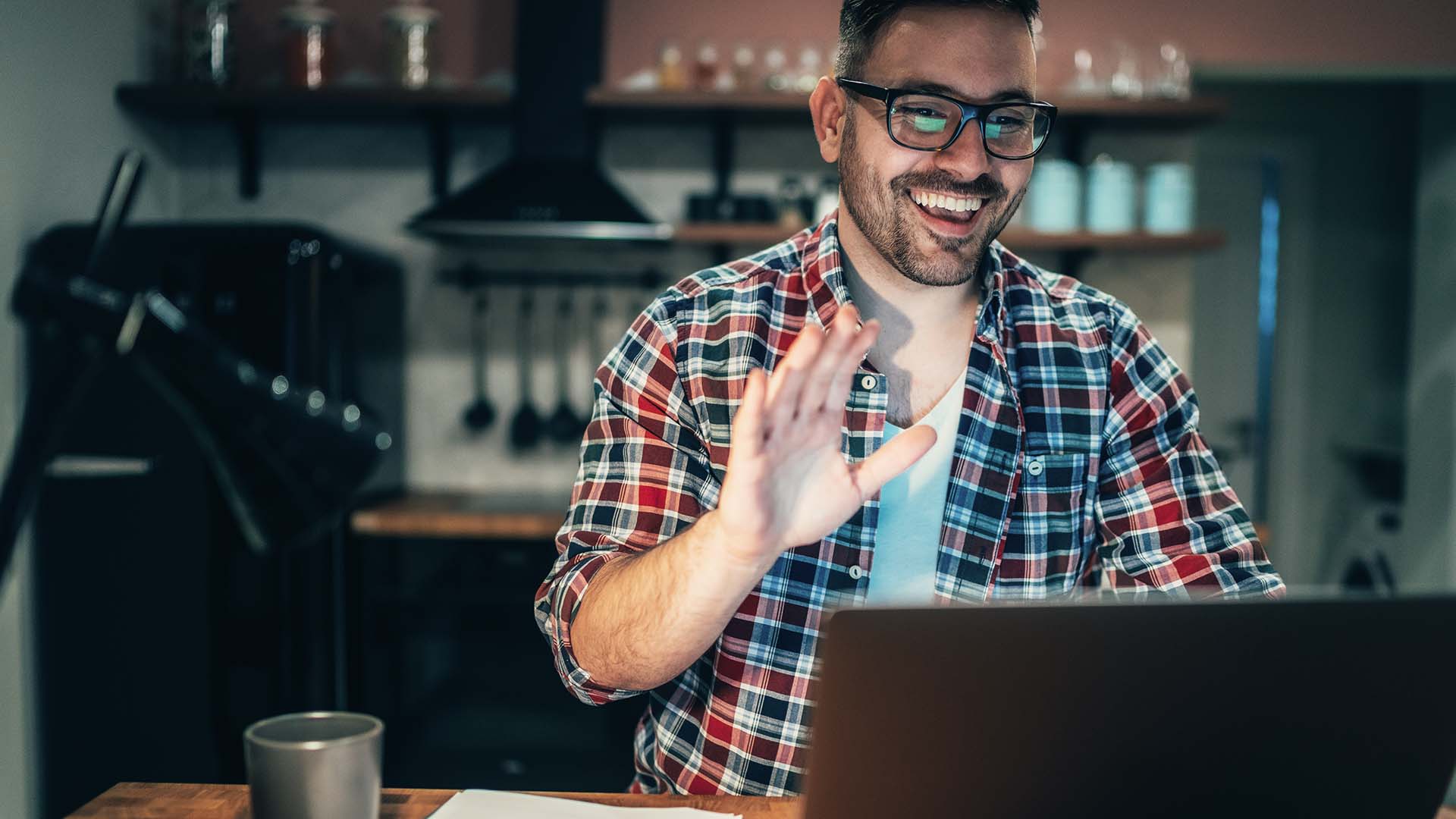 man smiling and waving on video conference