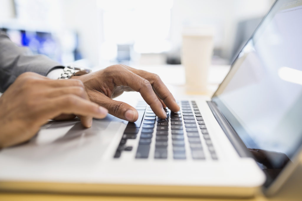 Close up photo fingers typing on laptop keyboard