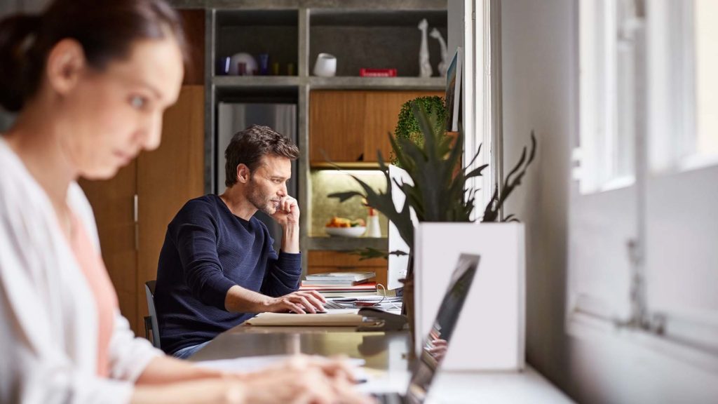 A man and a woman working at separate laptop computers