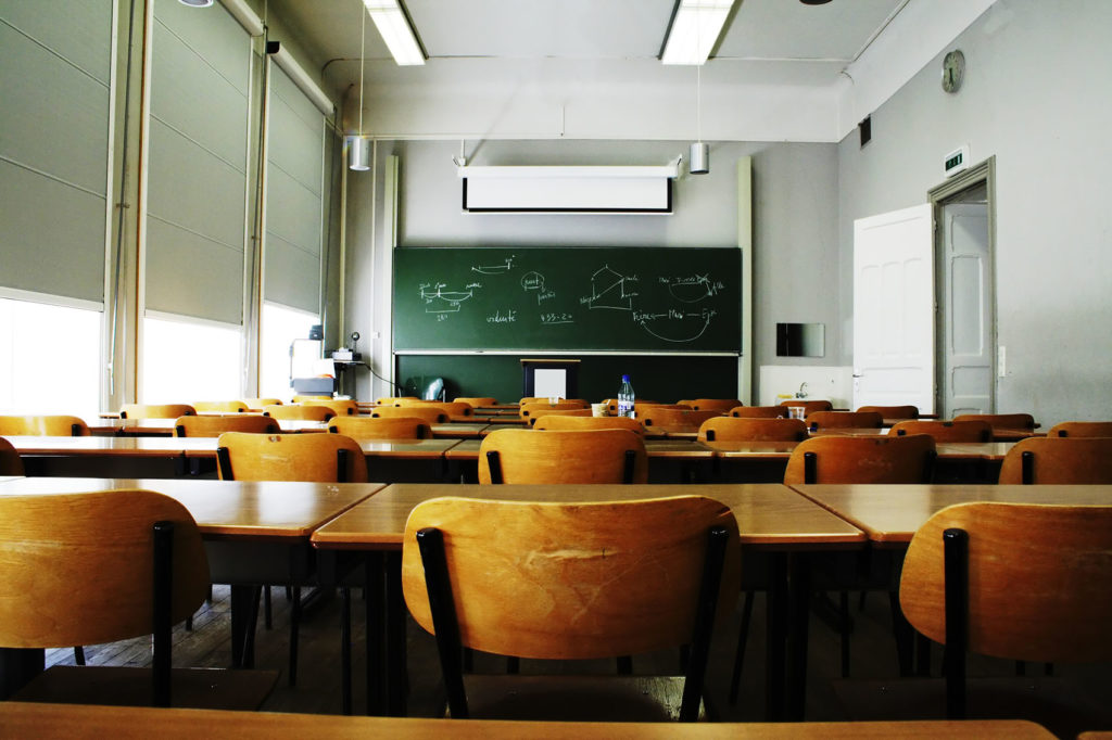 A large, empty classroom, lit by morning light.