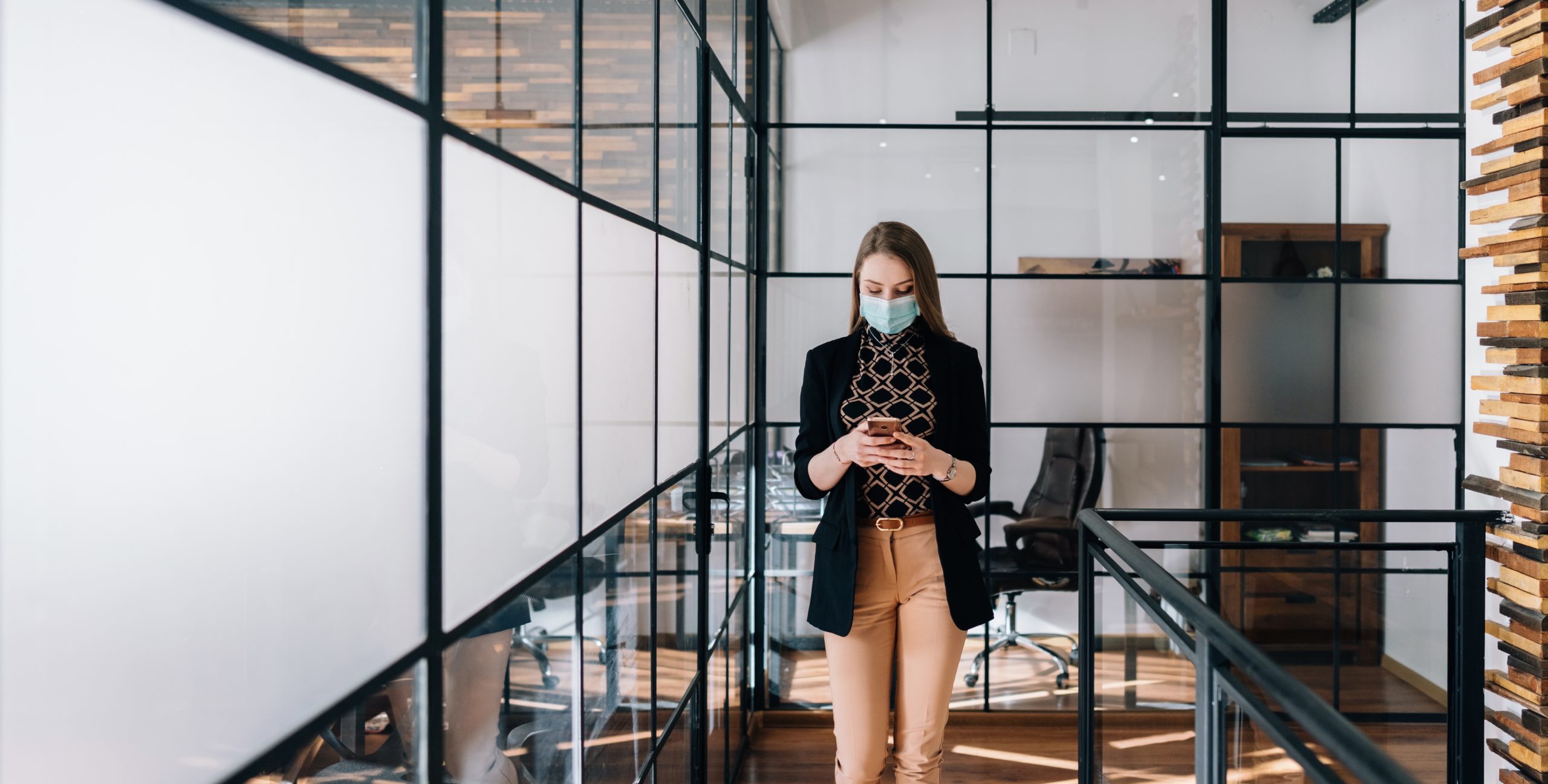 Businesswoman wearing mask in the office looking at her phone