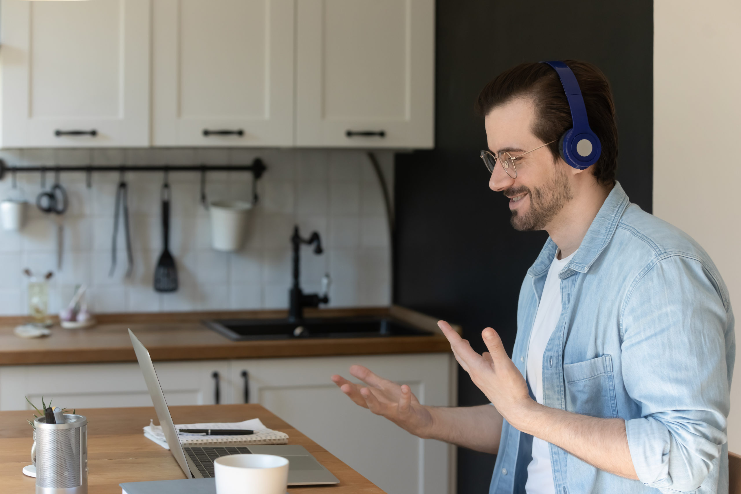 Side view smiling man wearing earphones at home, on a virtual interview.