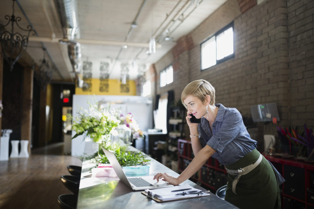 Florist working at laptop in flower shop