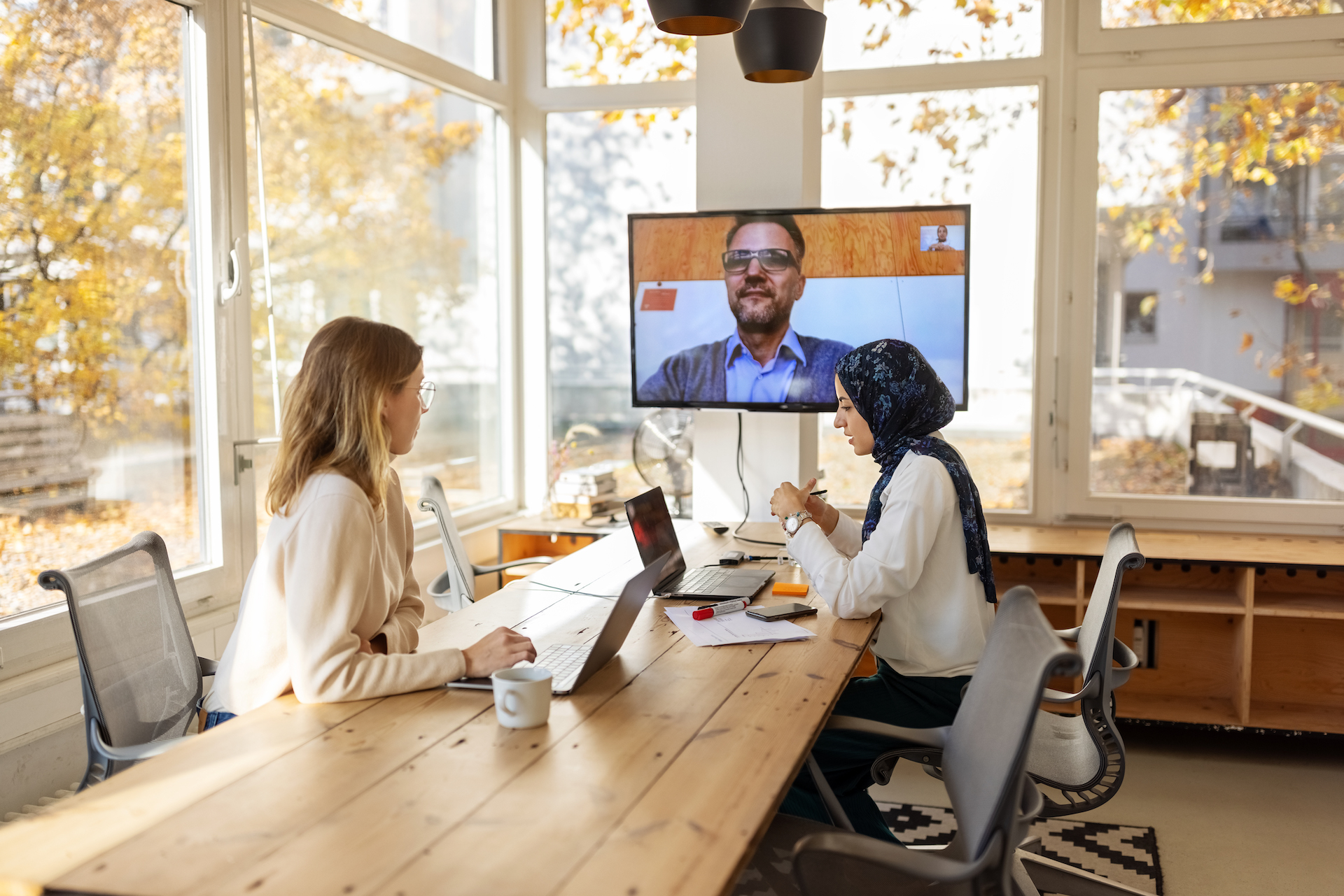 Photo of business colleagues having a zoom meeting in an office conference room.