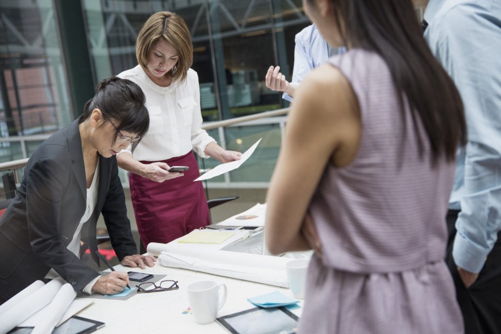 Businesspeople standing around conference table in meeting