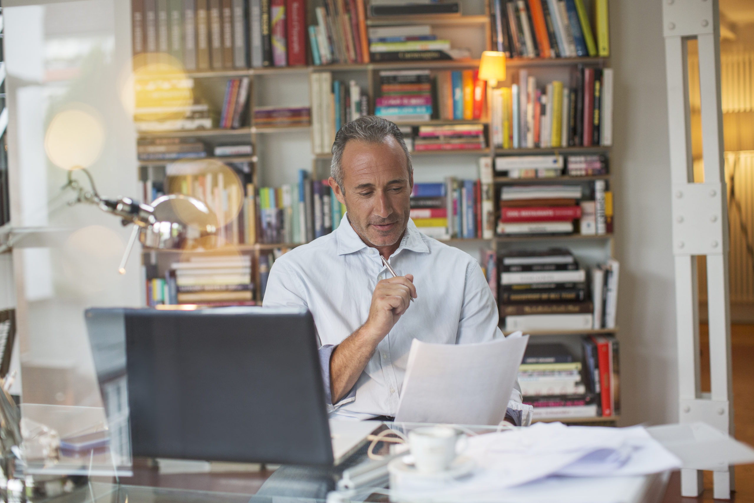 Businessman reading paperwork at home office desk