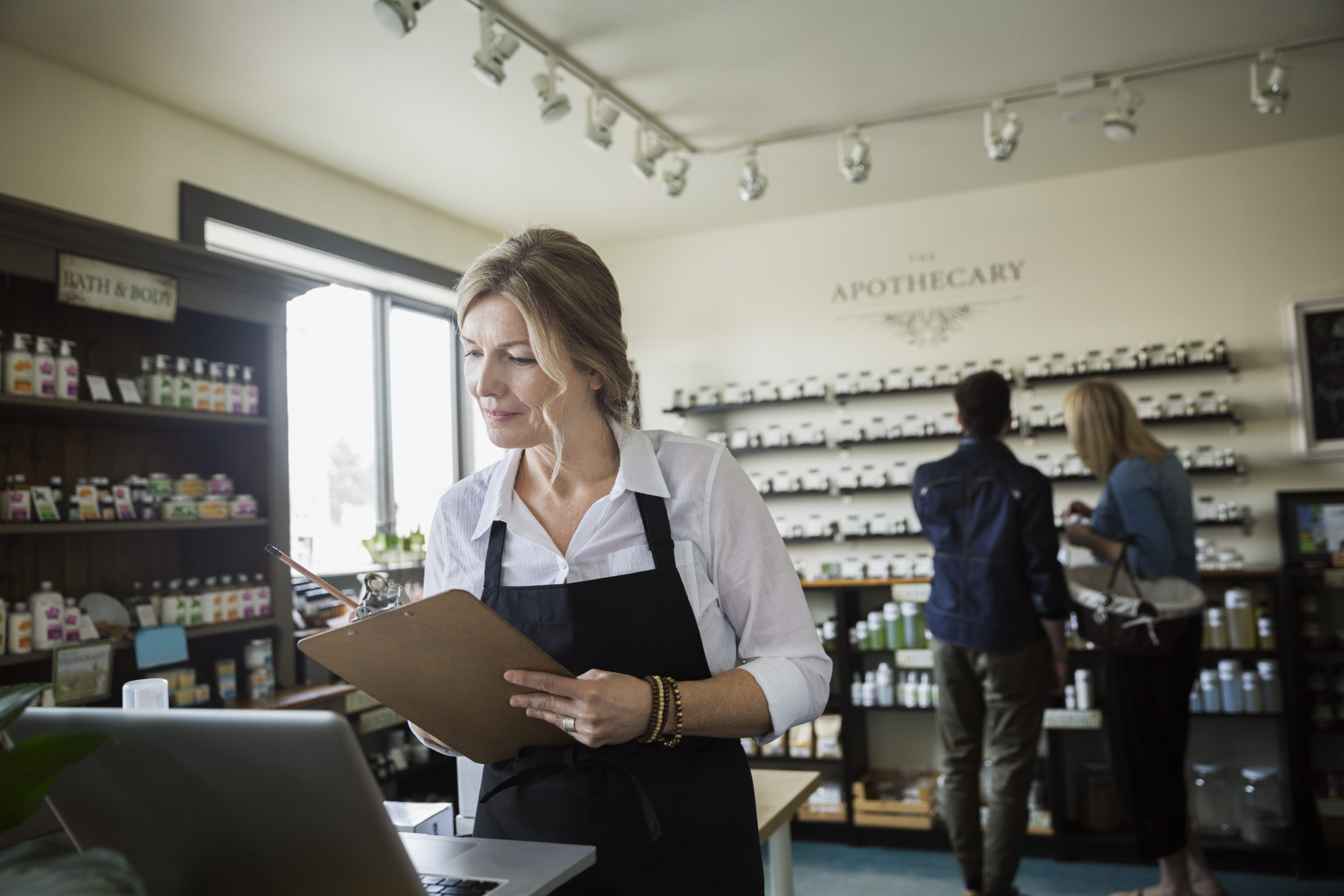 Apothecary shop owner checking inventory at laptop