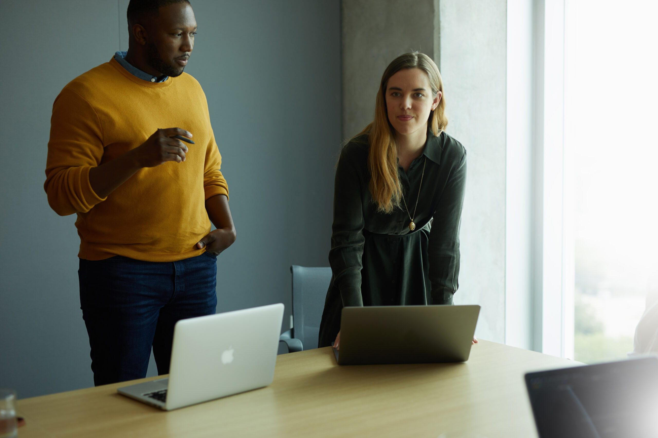 Colleagues in office standing in front of laptops