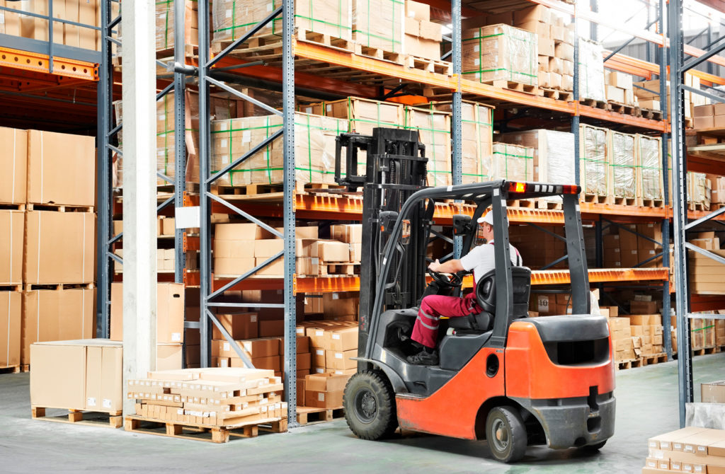 A forklift operator in action in a warehouse