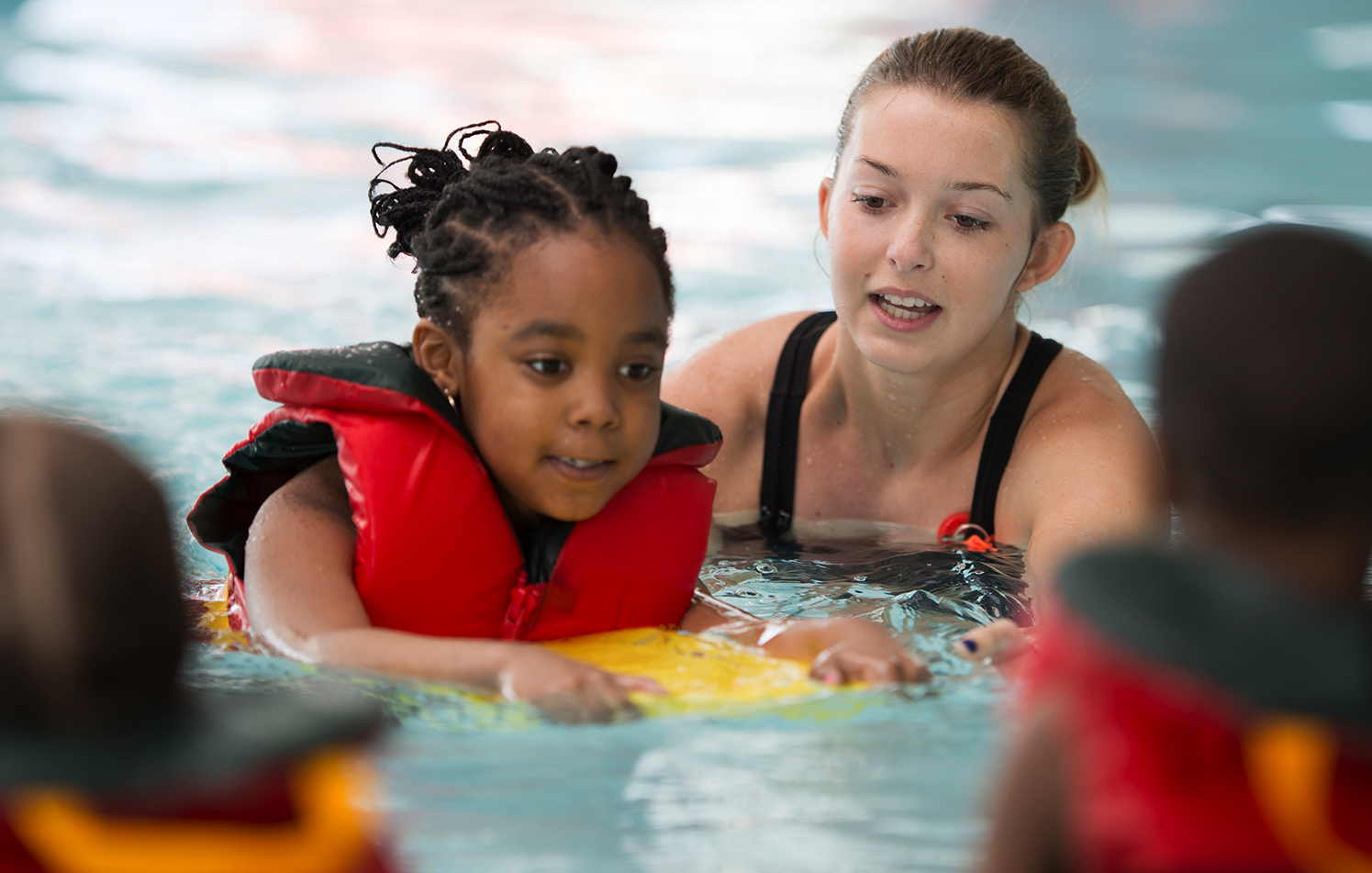 Young child learning to swim with an instructor in a pool