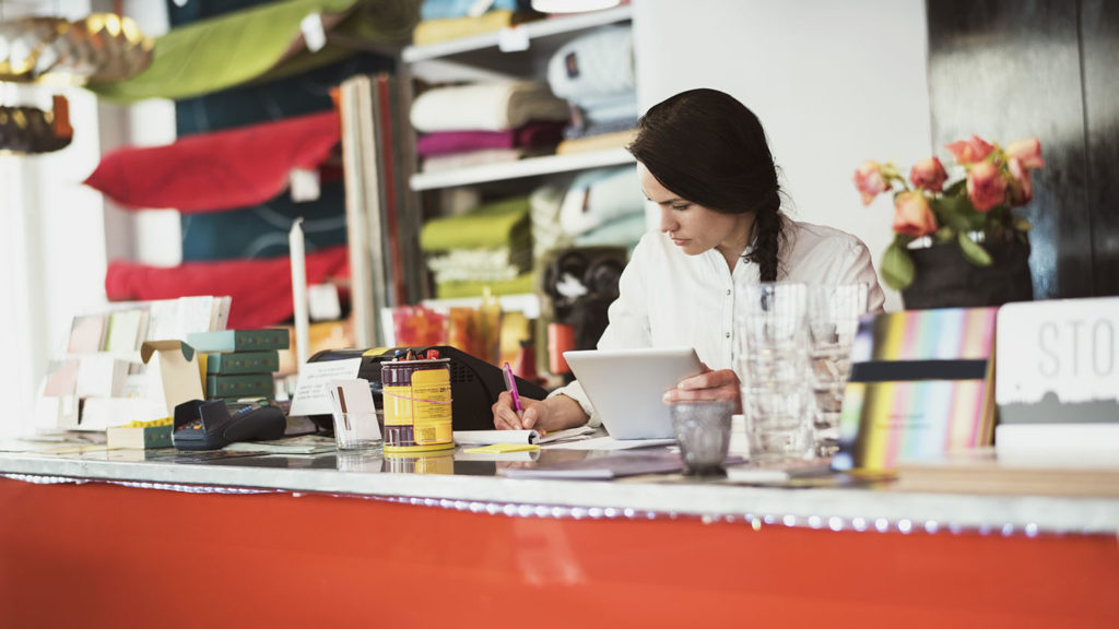 A woman working at a desk with a tablet and pen.