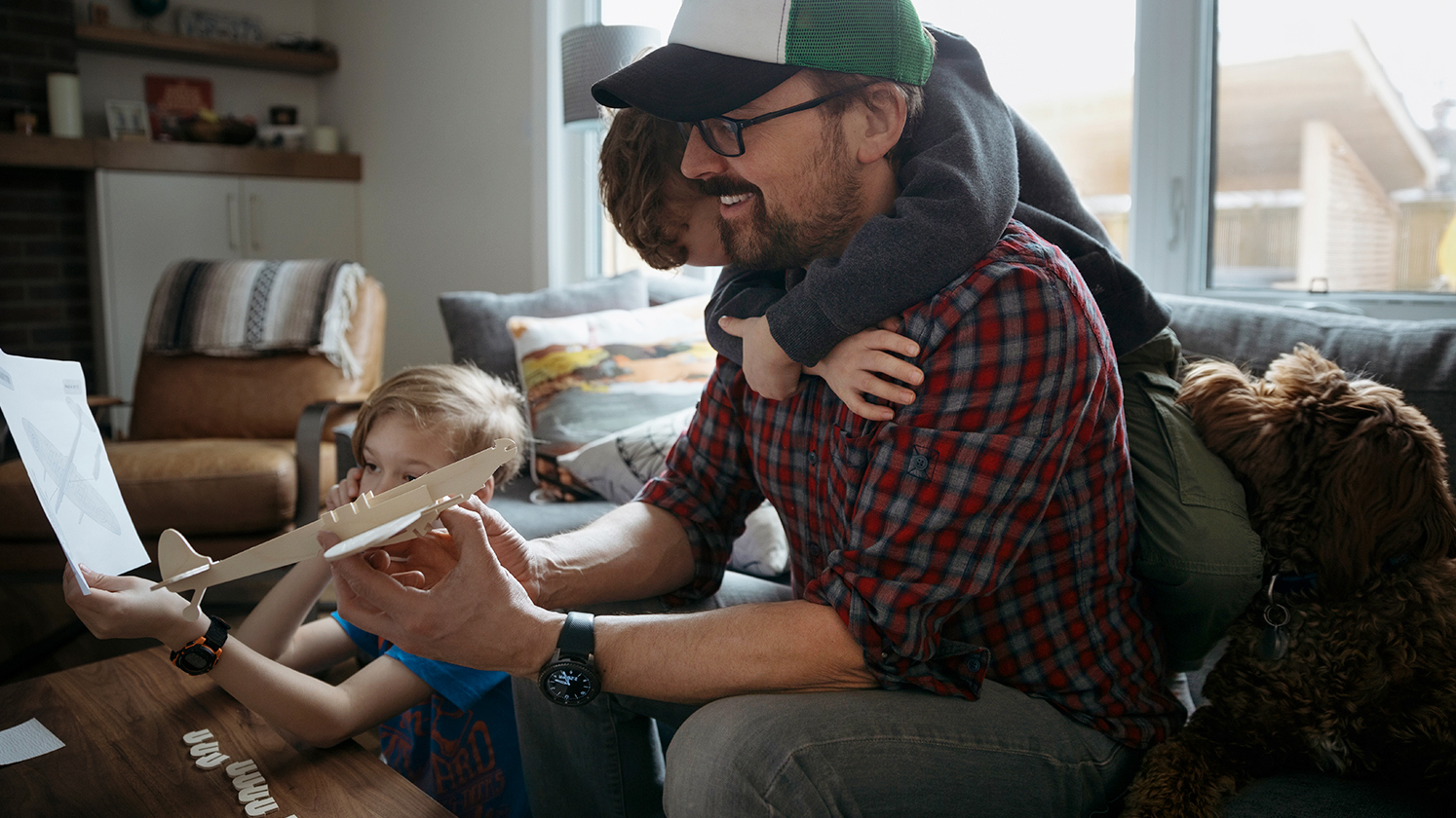 Father with two sons building a model airplane in their living room