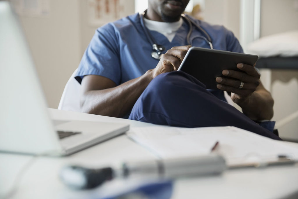 Doctor in scrubs using digital tablet in clinic.