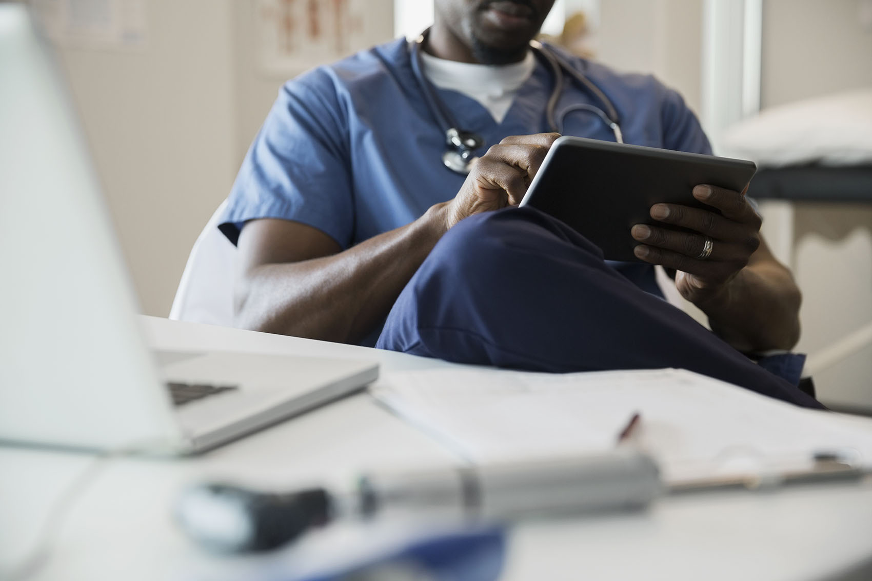 Doctor in scrubs using digital tablet in clinic