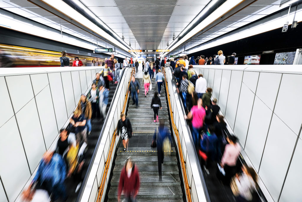 An aerial view of stairs to a train station platform during rush hour.