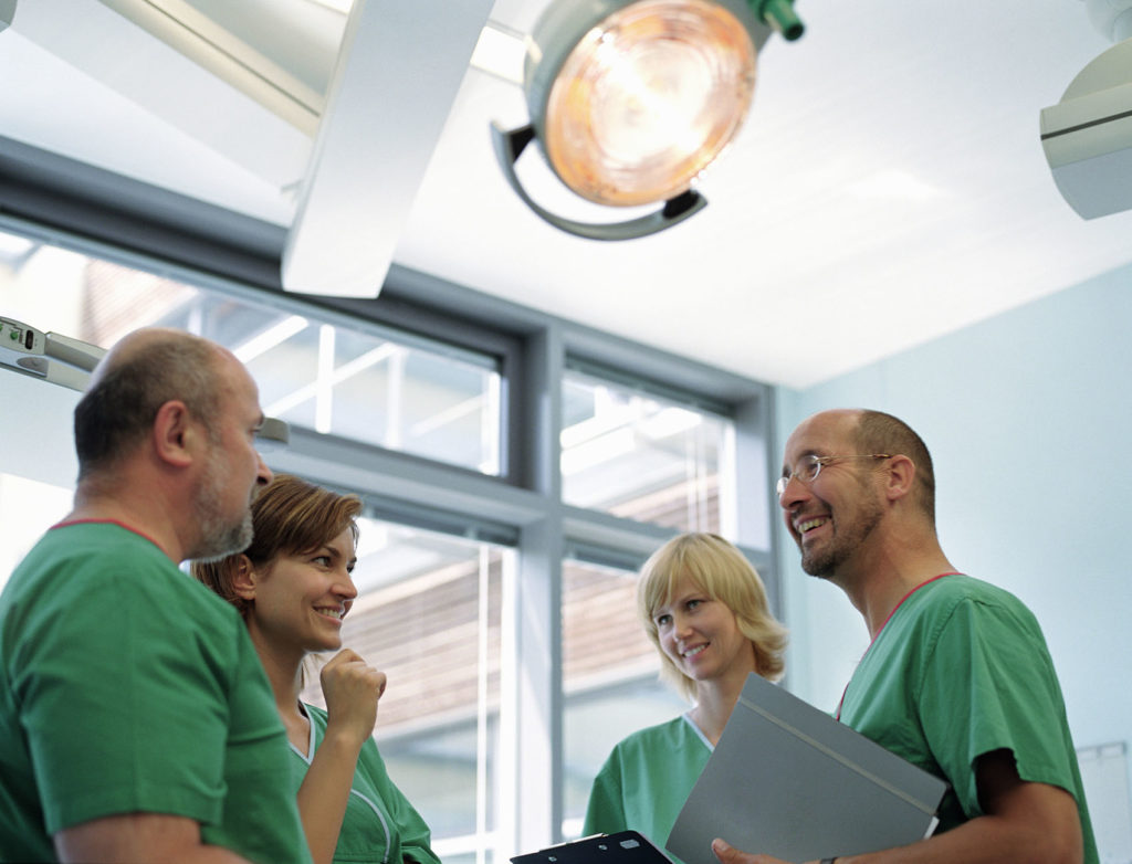 Two mature male doctors and two female nurses talking