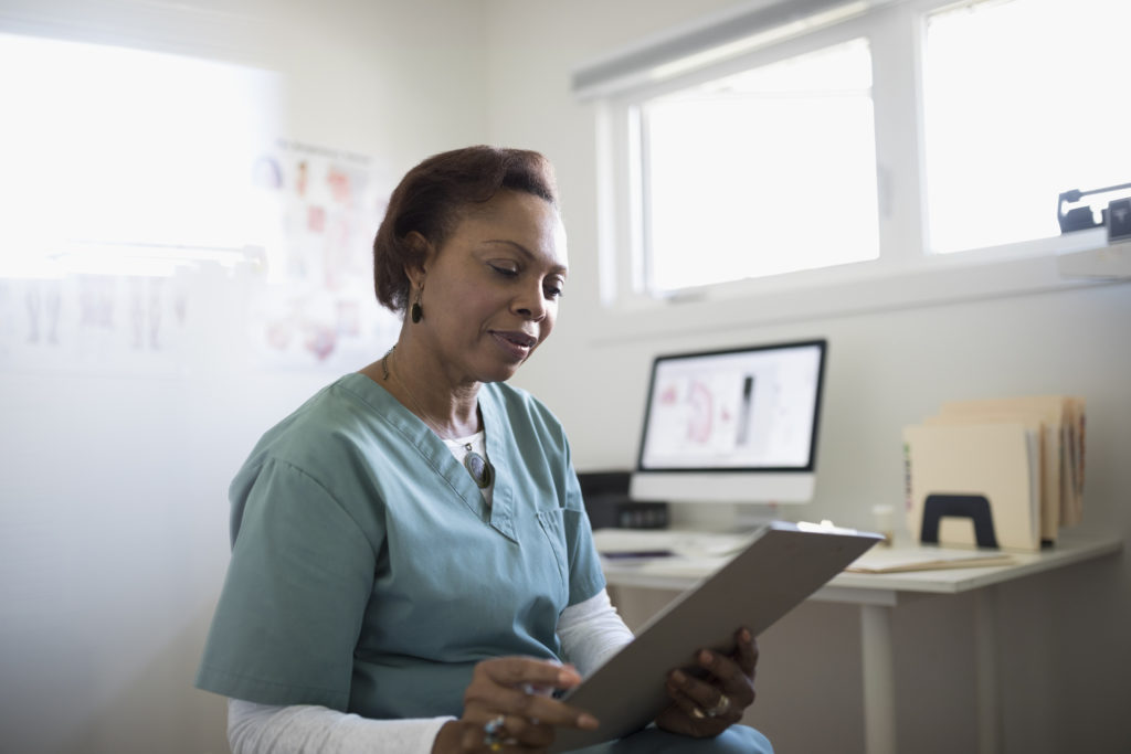 Mature female doctor reviewing medical record in doctor's office.