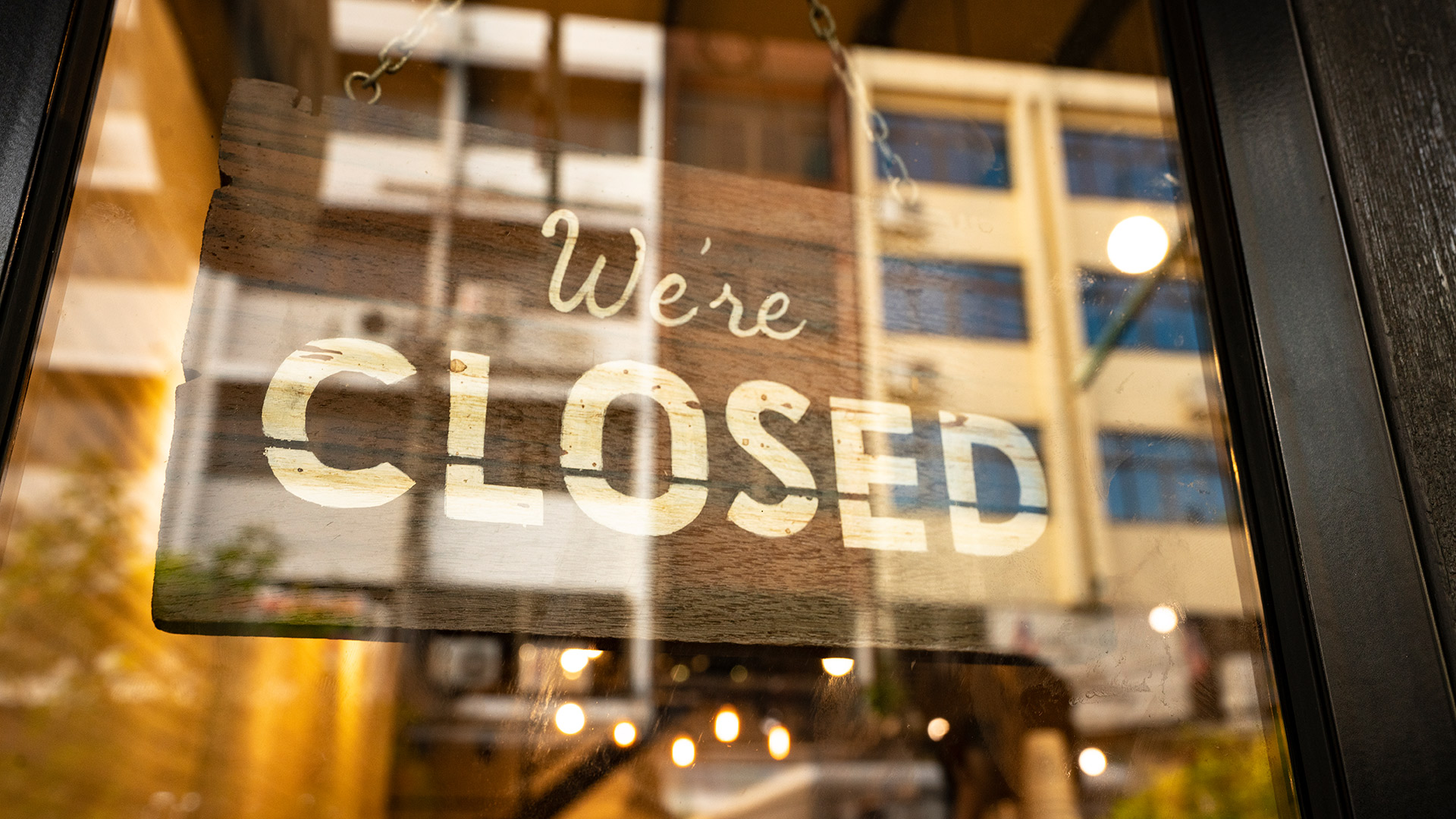 Closed sign hanging in business window.