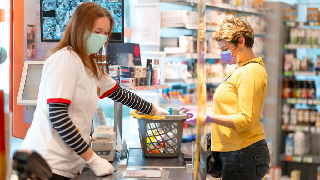 A cashier ringing through a customer's shopping, both wearing masks.