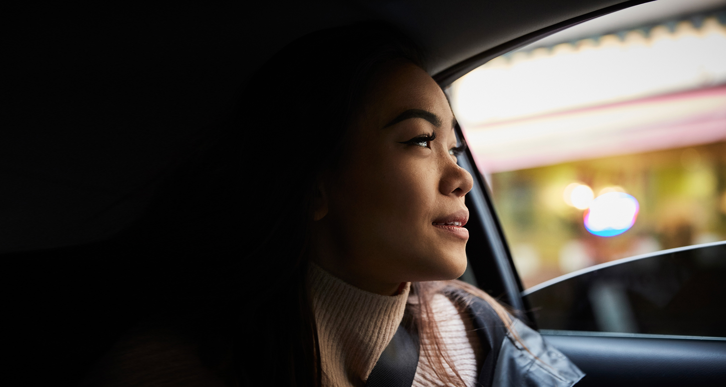 Woman in car staring out the window contemplatively
