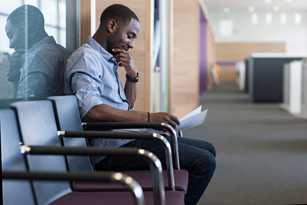 Man sitting on chair preparing for an interview by reading notes