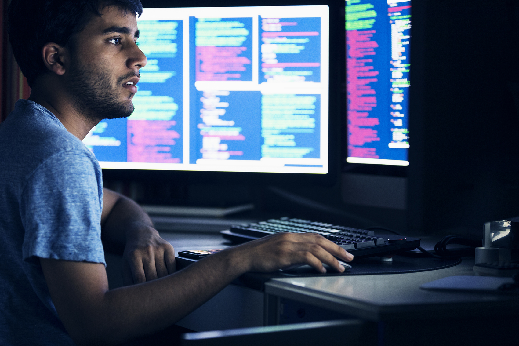 Computer programmer looking at two computer screens