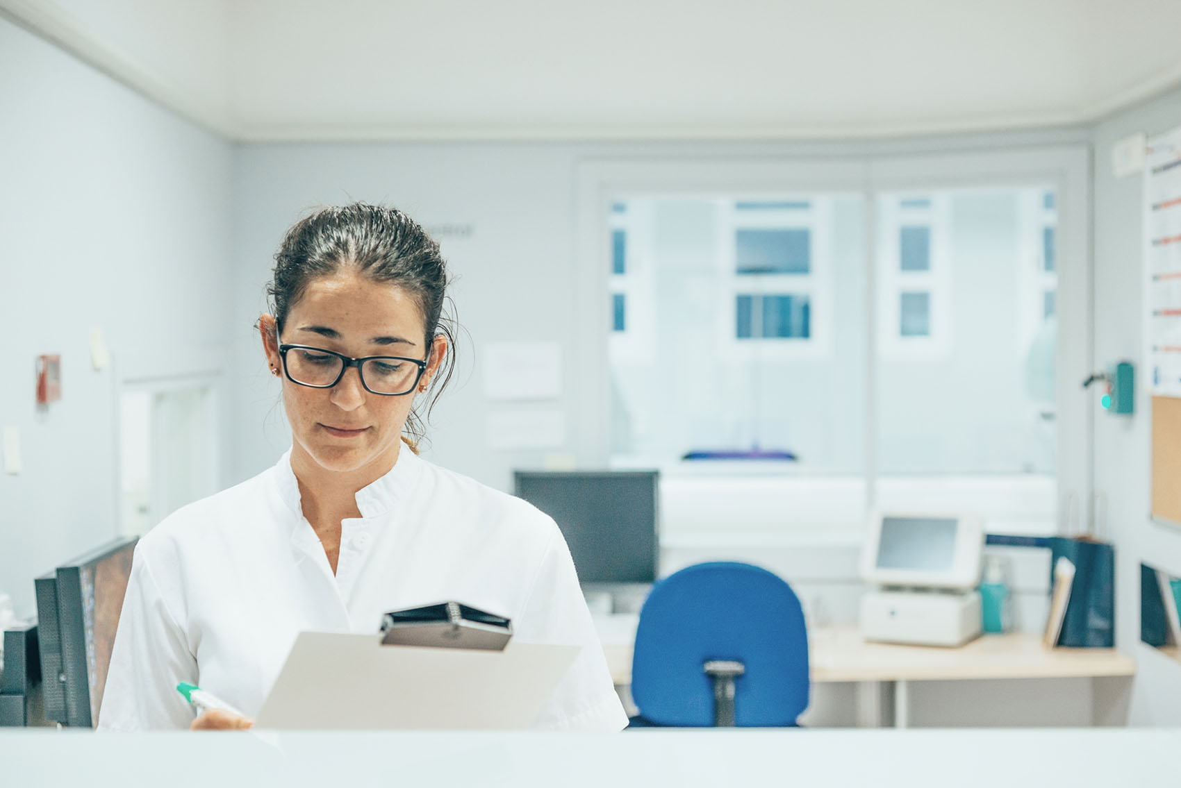 A healthcare worker in her office writing something on a notepad