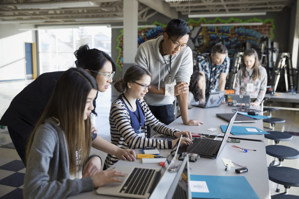 Photo of current employees helping train interns while seated at desks